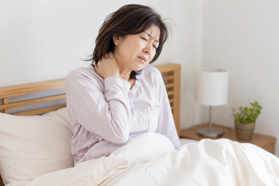朝起きたら首が痛くて首を押さえる50代女性