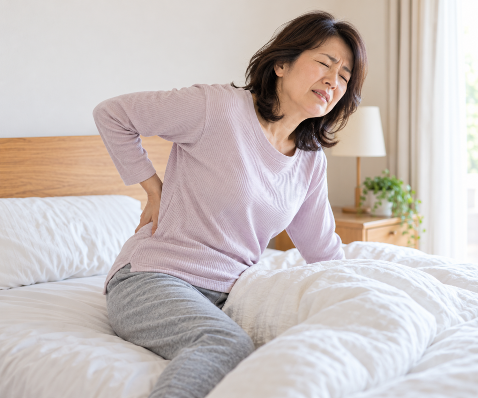 朝起きて腰を押さえている50代女性